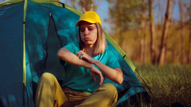Woman scratching mosquito bite at camp