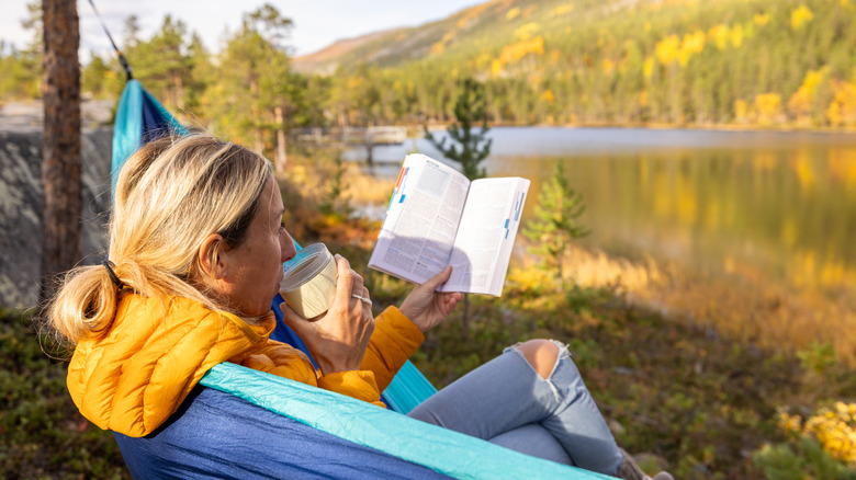 Lone camper reading by lake