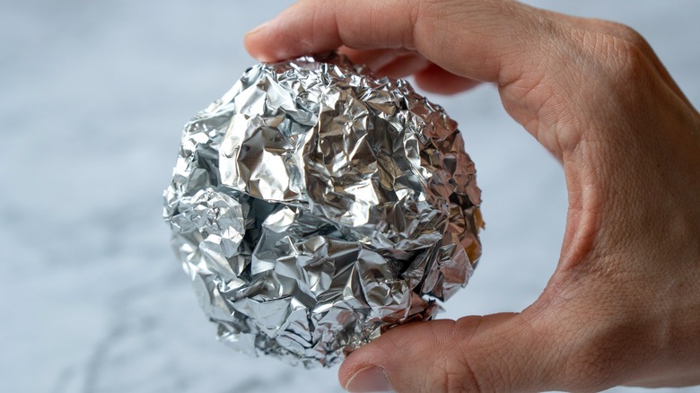 hand holding ball of aluminum foil