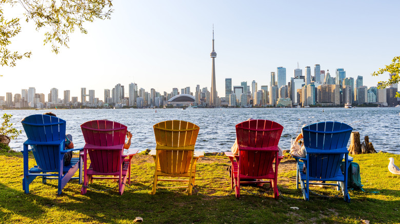 A row of color chairs perched along the shoreline on Toronto Island