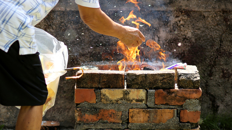 A man tending to a fire in a square brick fire pit