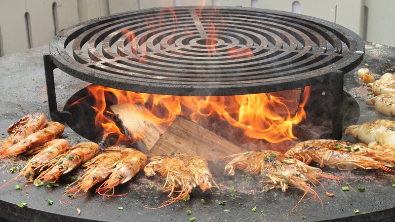 Cooking grate set over a hot fire pit, with grilled shrimp