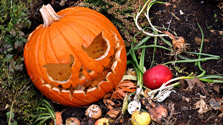 A jack-o'-lantern in a compost pile