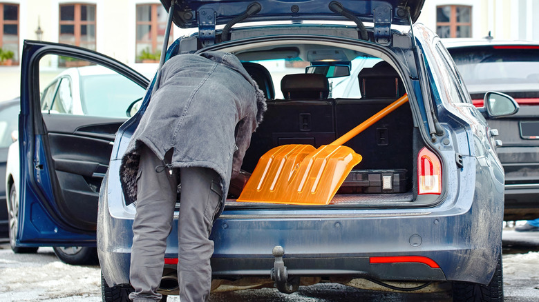Man loading snow shovel in car