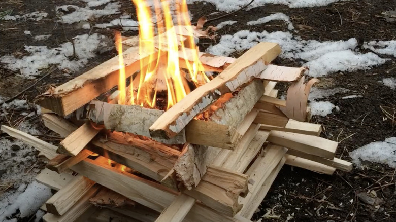 Logs stacked parallel and perpendicular to create log cabin fire