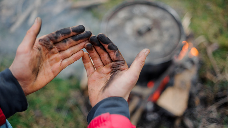 Dirty hands and a campfire in the background