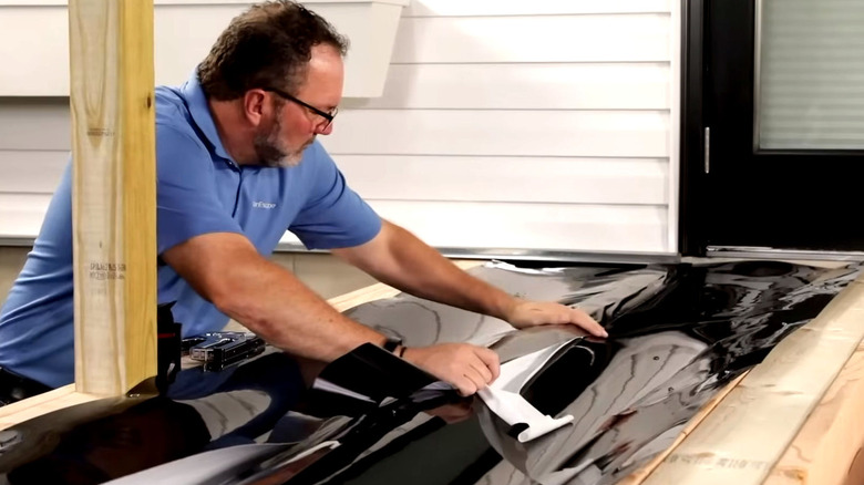 Someone installing an under-deck drainage system