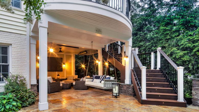 A deck with a swing and a TV underneath