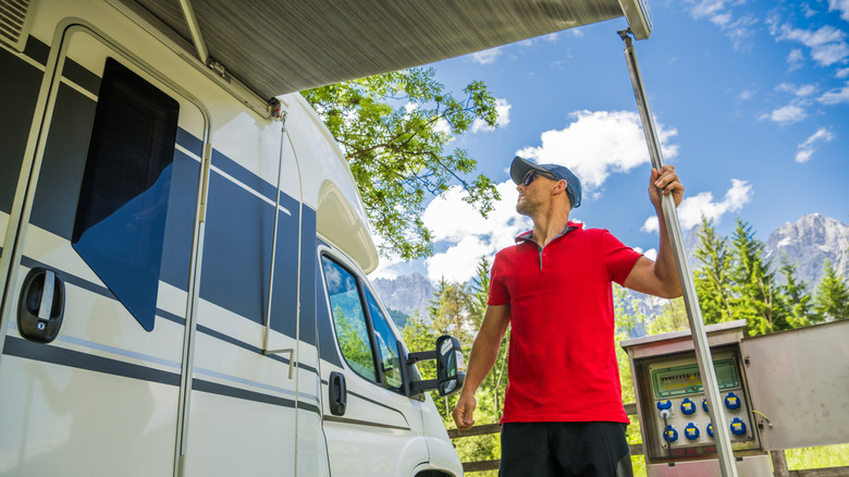 A man pulling out his RV on his camper with mountains and blue sky in the background