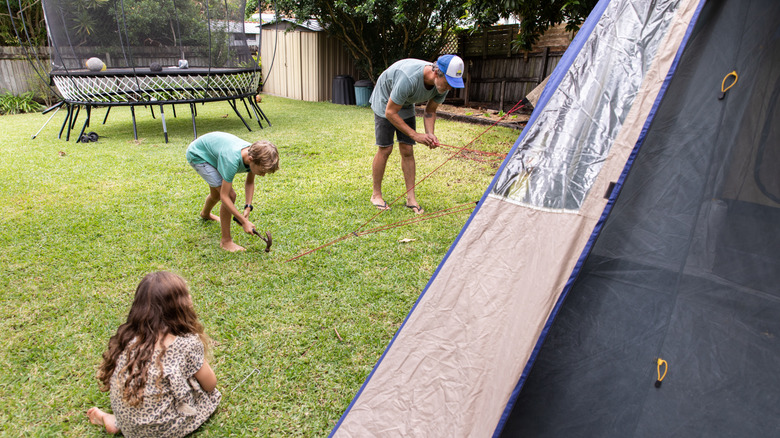 man and children testing a tent in backyard