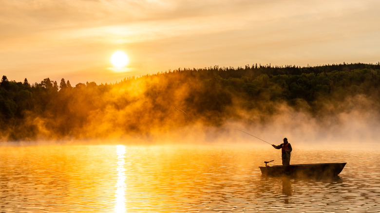 Person casting from small boat at sunrise