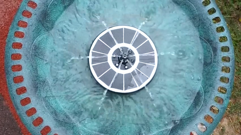 solar disc-shaped fountain in a green birdbath.