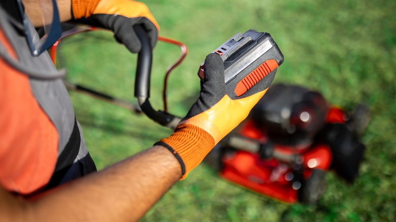 Removing battery from electric lawn mower on lawn