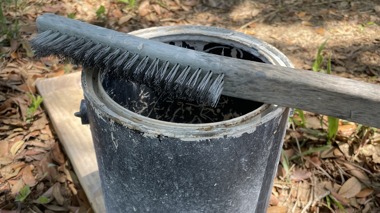 An empty paint can with a wire brush