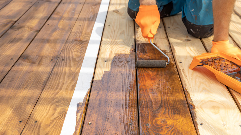 Person staining a wood deck