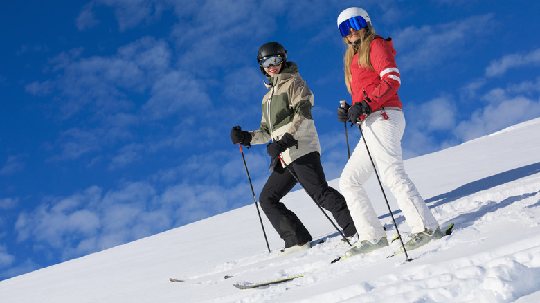 Two skiers smiling while on a snowy slope