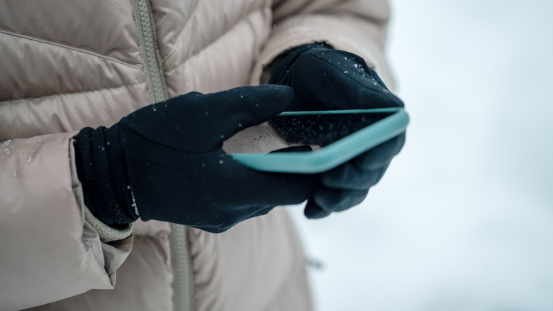 Person using smart phone outdoors in the snow