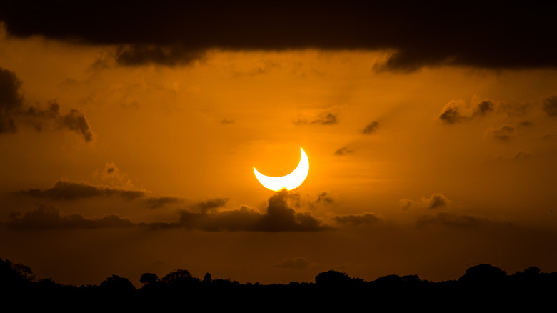 Partial solar eclipse in cloudy dark sky
