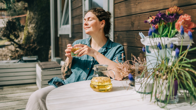 Woman sitting at a table on porch with drink