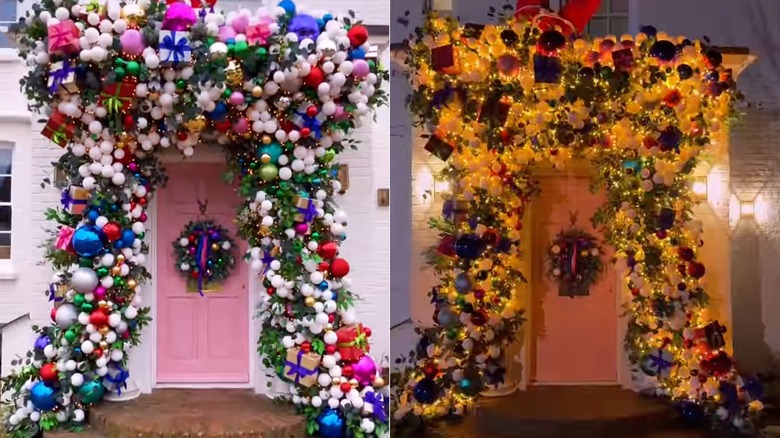 A pink front door surrounded by a garland filled with presents and ornaments
