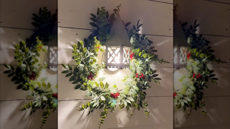 A lantern-style porch light with a wreath hanging around it