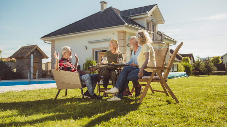 People socializing in an open backyard among several houses
