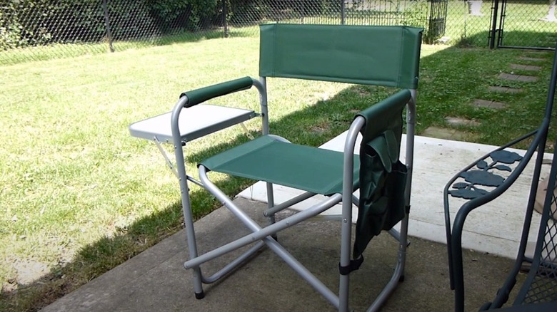 A green Harbor Freight folding aluminum sports chair sitting on a patio.
