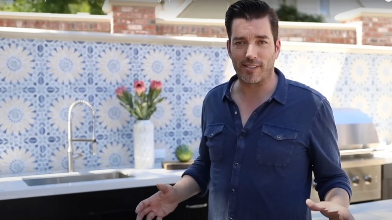 Jonathan Scott in his outdoor kitchen, with blue tile backsplash in background.