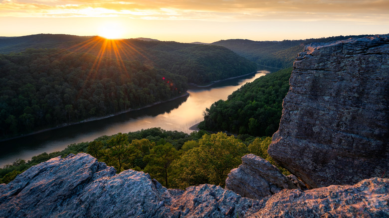 Sunset over a river with large rock walls inthe foreground