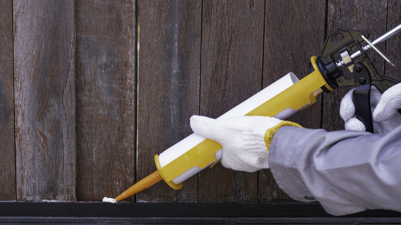 applying caulk or adhesive to a building