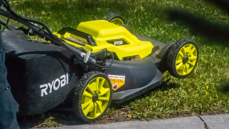 Ryobi mower raised to its rear wheels on a lawn