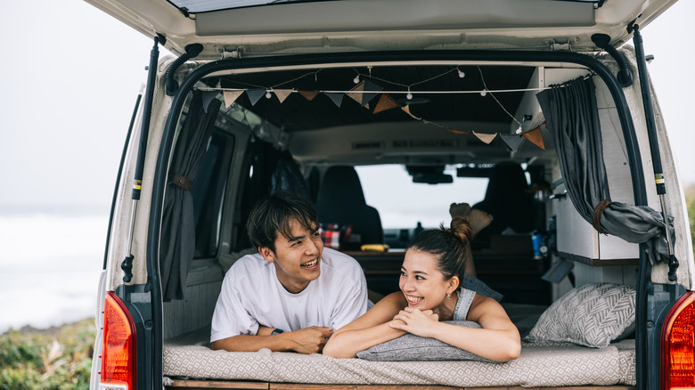 two people in a bed set up in a van