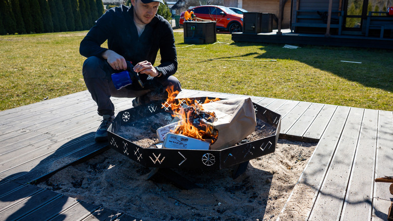 Person burning paper bag and other materials in a fire pit