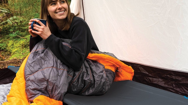 Woman sitting on a Cascade Mountain Tech cot in the morning