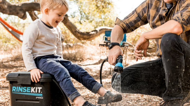 Father spraying child's dirty shoes using a RinseKit Pro portable shower