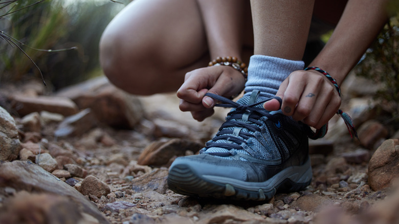Person tying their shoe on a trail