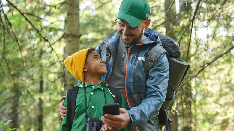 A man and boy hiking, the man holding a smartphone