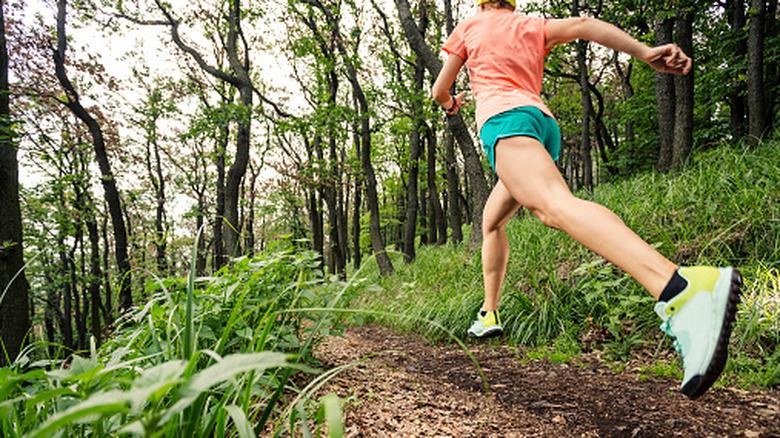 Women trail running in a lush forest