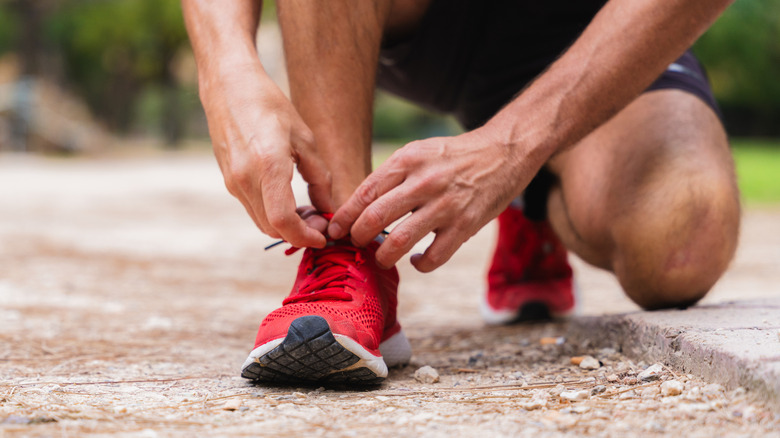 Trail runner bending down to tie their shoe