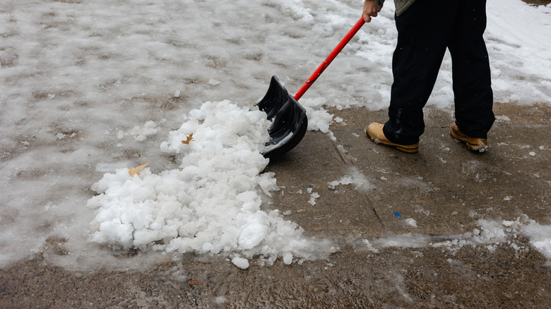 A person scraping ice off a sidewalk