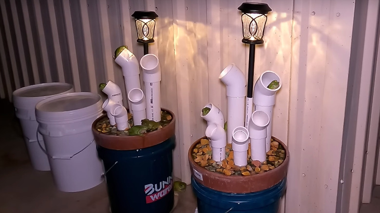 Two frog hotels at night with various pipe sizes, elbows, and a solar light