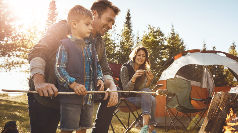 Family roasting marshamallows by a tent