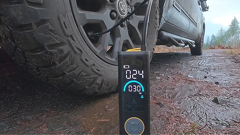 Fanttik S200 Apex air pump filling a truck tire in a forest