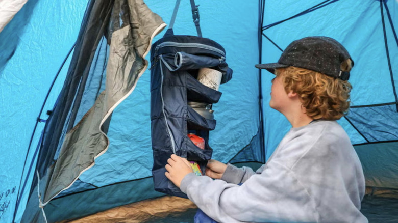 Person in a tent, reaching into Grand Trunk hanging shelf organizer