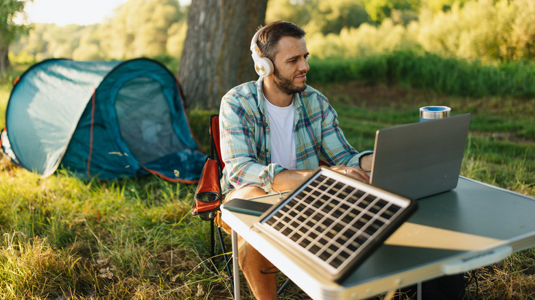 Camper at a campground with laptop and headphones