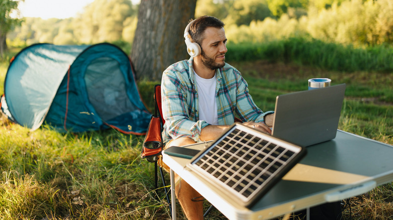 Camper at a campground with laptop and headphones
