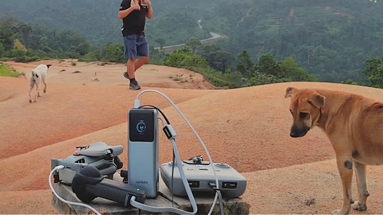 Social media hiking creator charging drone outdoors with UGreen Nexode power bank