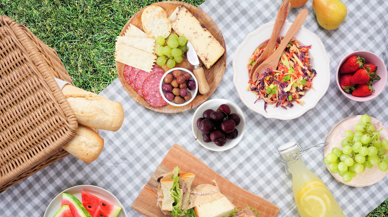 A large spread of exposed food arranged on a picnic blanket