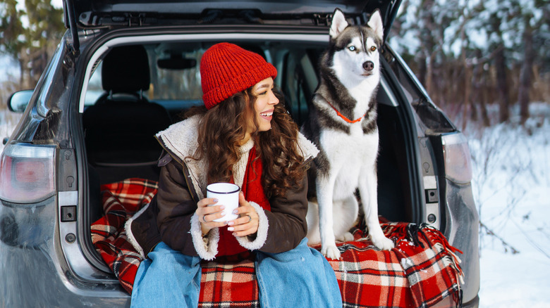 Woman and dog sitting in tailgate of a car