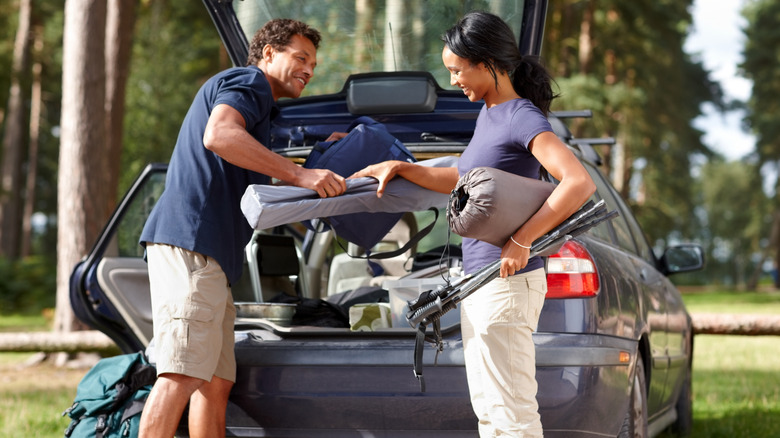 Young couple unpacking camping gear from a car